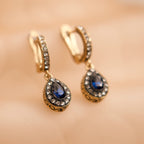 Gold earrings with blue gemstones on a blurred background