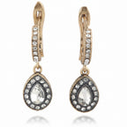 Pair of gold and silver earrings with teardrop-shaped gemstones on a white background