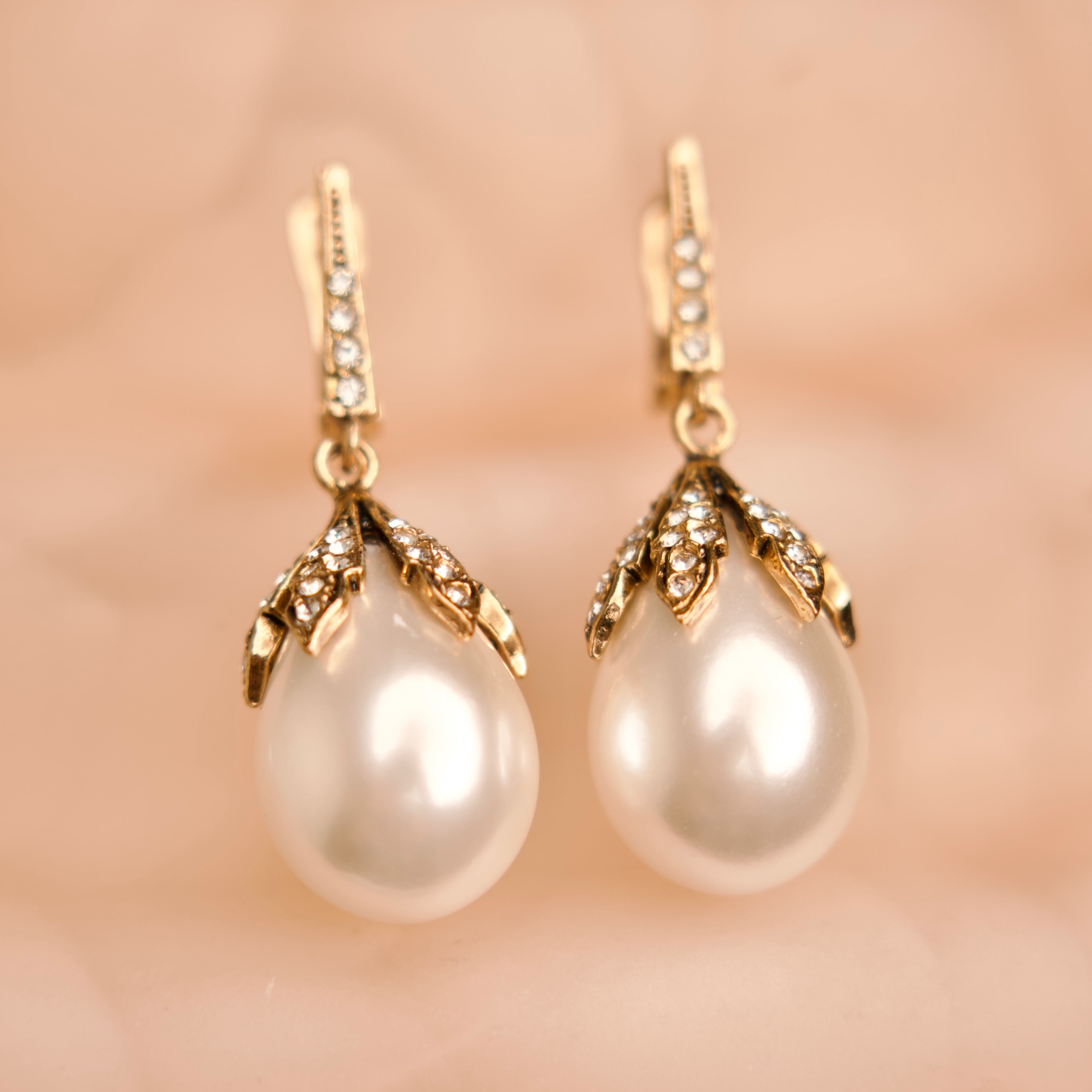 Pearl earrings with gold accents on a soft pink background