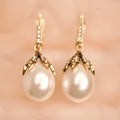 Pearl earrings with gold fixtures on a soft pink background