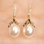 Pearl earrings with gold fixtures on a soft pink background