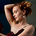 Woman in a dark red dress sitting indoors with a blurred background