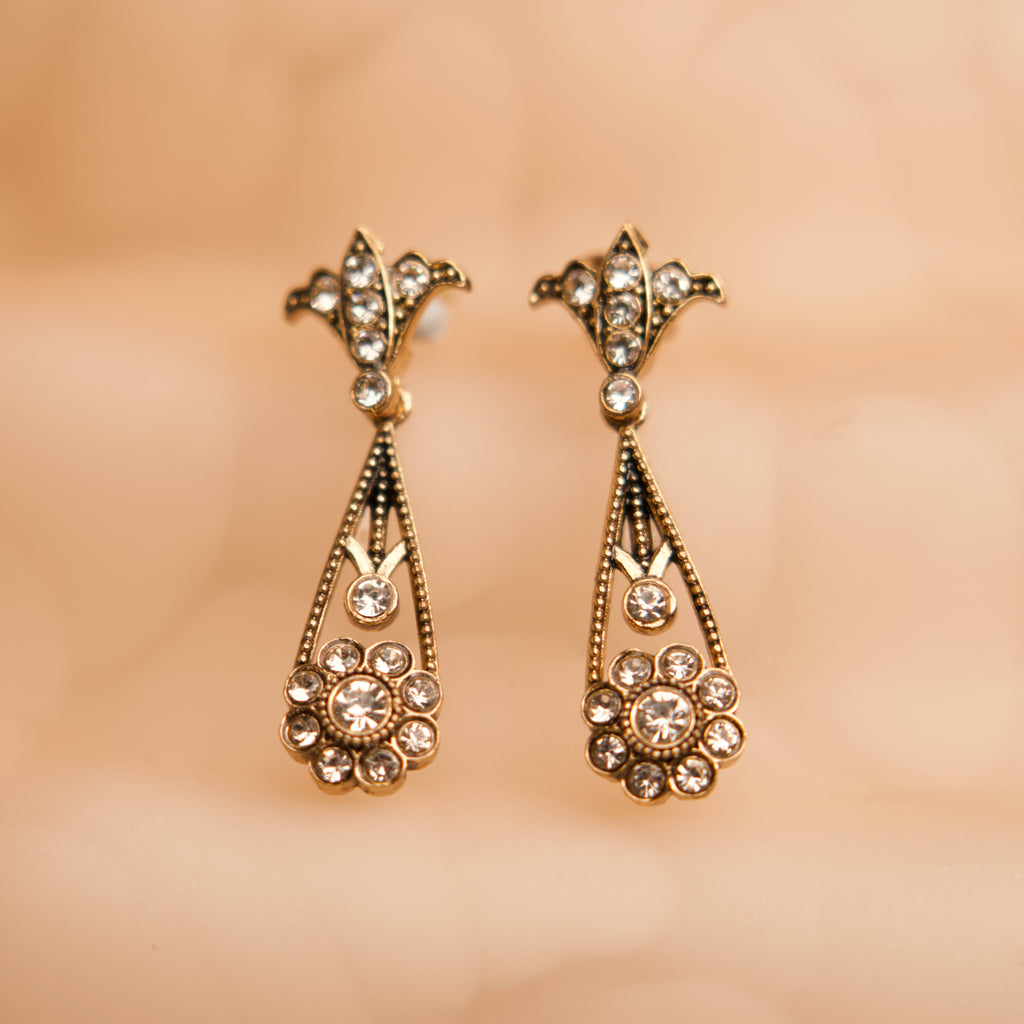 Gold earrings with gemstones on a beige background