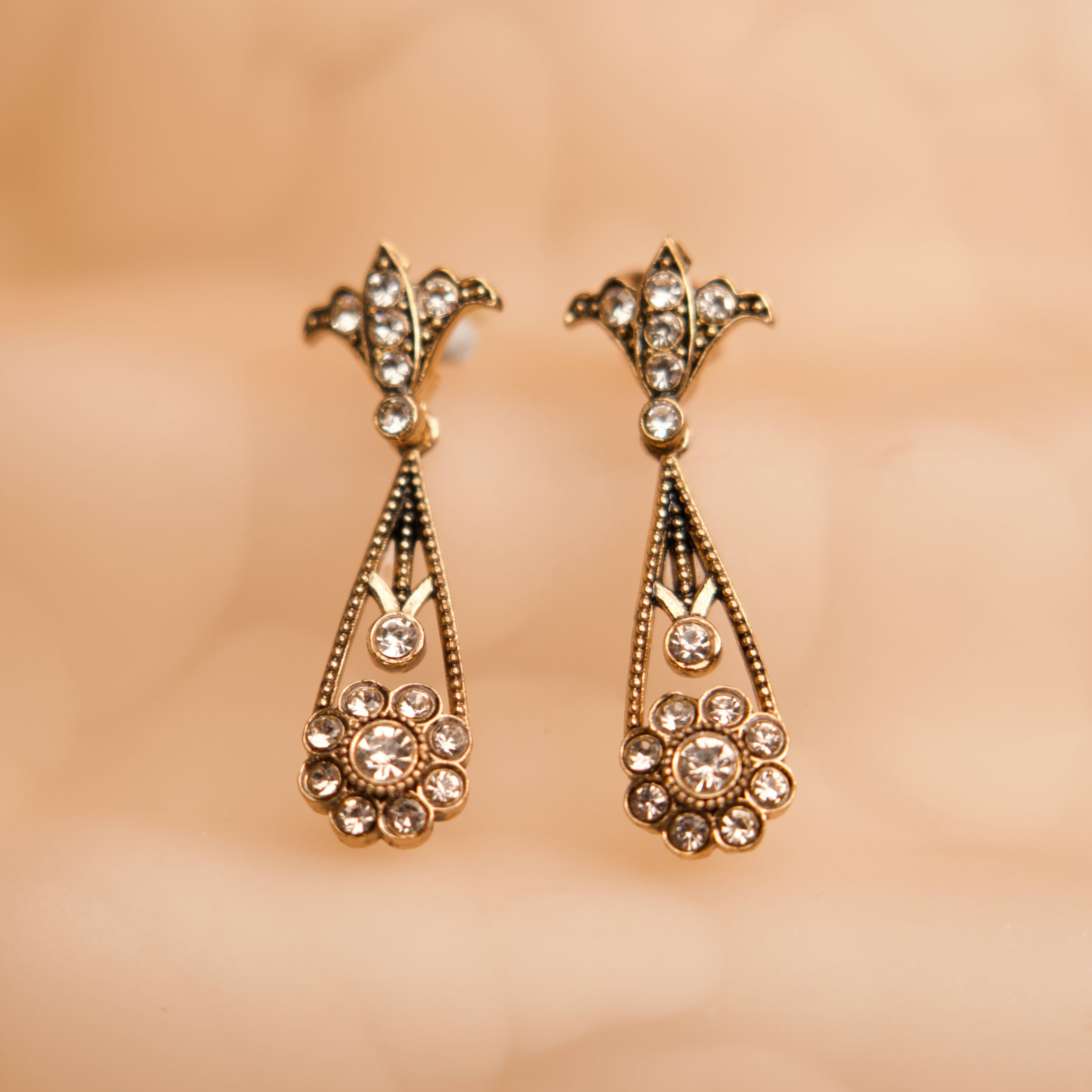 Gold earrings with gemstones on a beige background