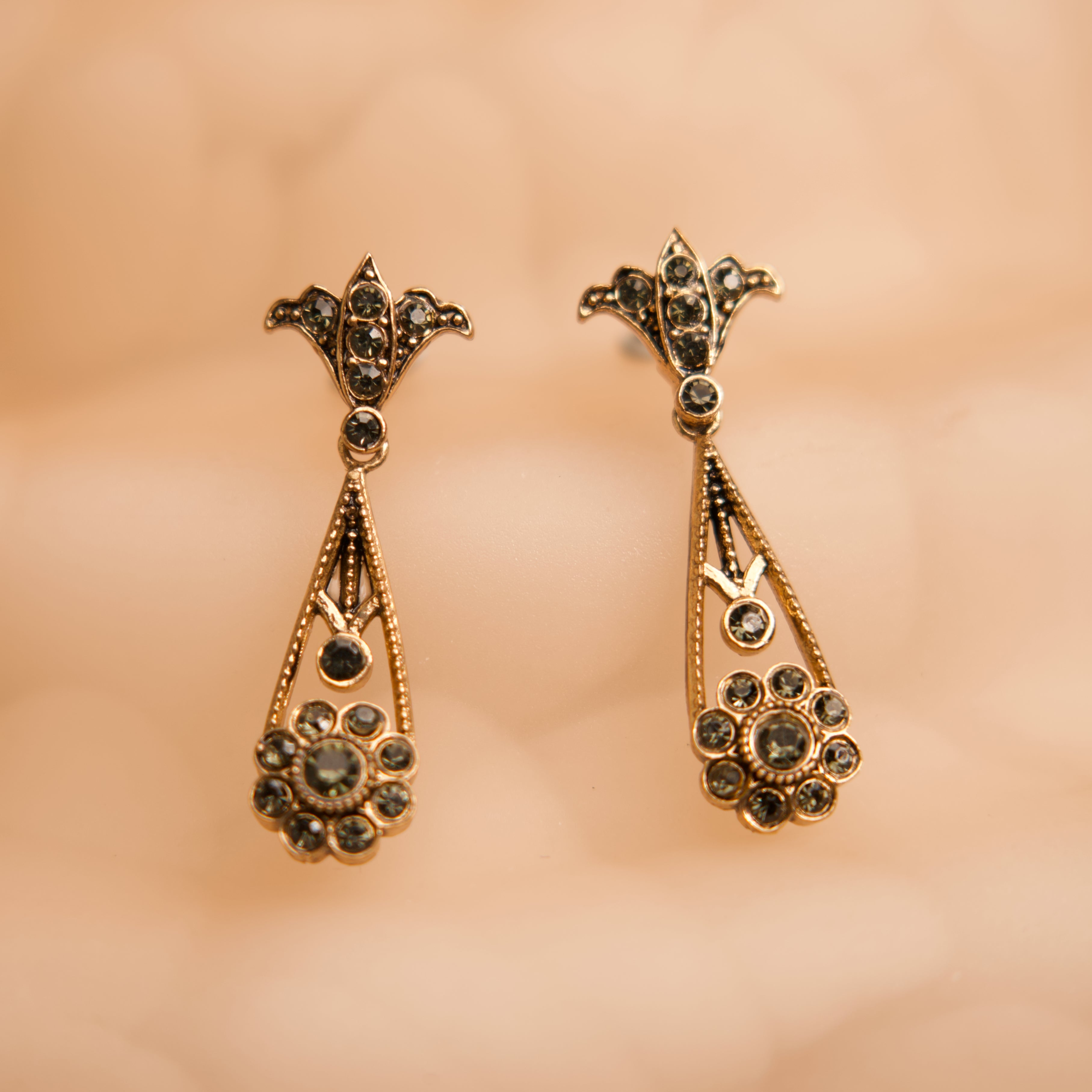 Pair of gold earrings with gemstones on a beige background