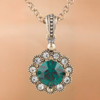 Gold necklace with a green gemstone pendant on a beige background