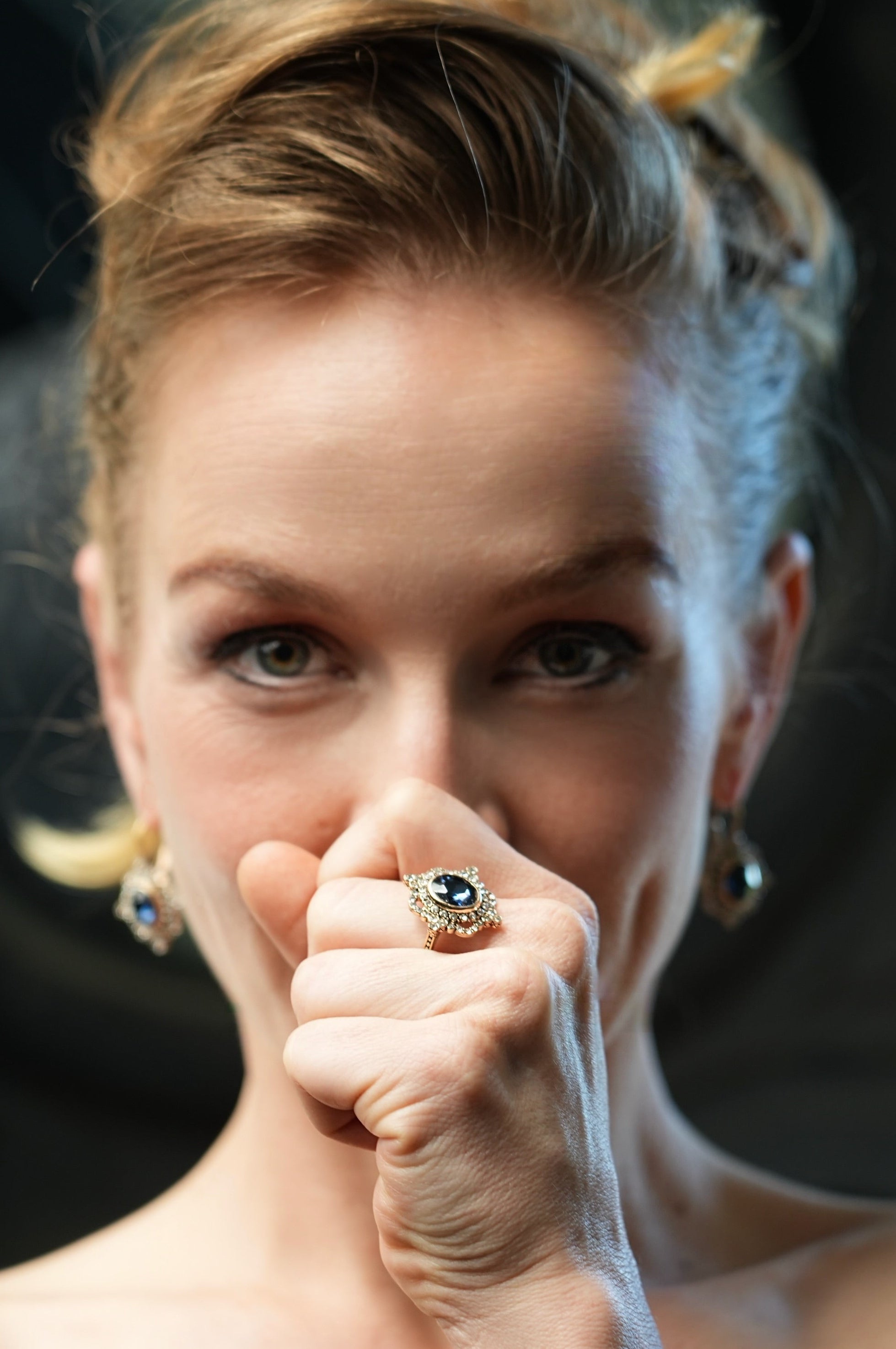 Woman with a ring on her finger holding a white string against a dark background