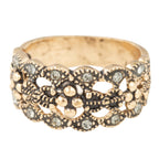 Gold ring with intricate design and embedded stones on a white background