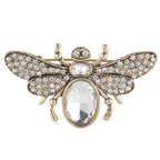 Gold bee-shaped brooch with crystal stones on a white background