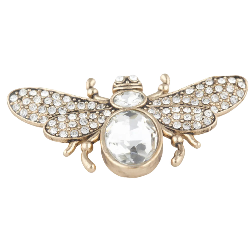 Gold bee-shaped brooch with crystal details on a white background