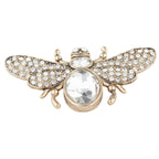 Gold bee-shaped brooch with crystal details on a white background