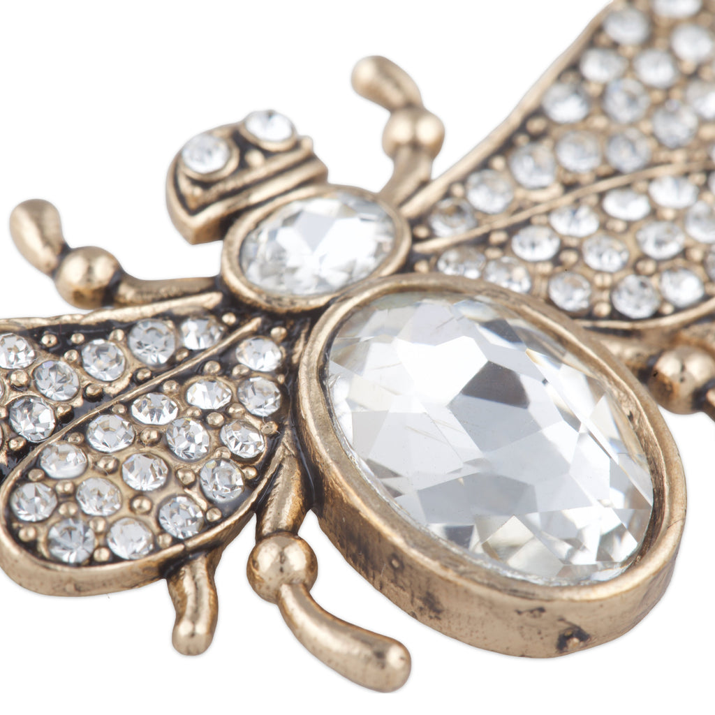 Decorative bee-shaped object with crystal-like stones on a white background
