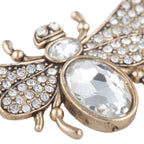 Decorative bee-shaped object with crystal-like stones on a white background