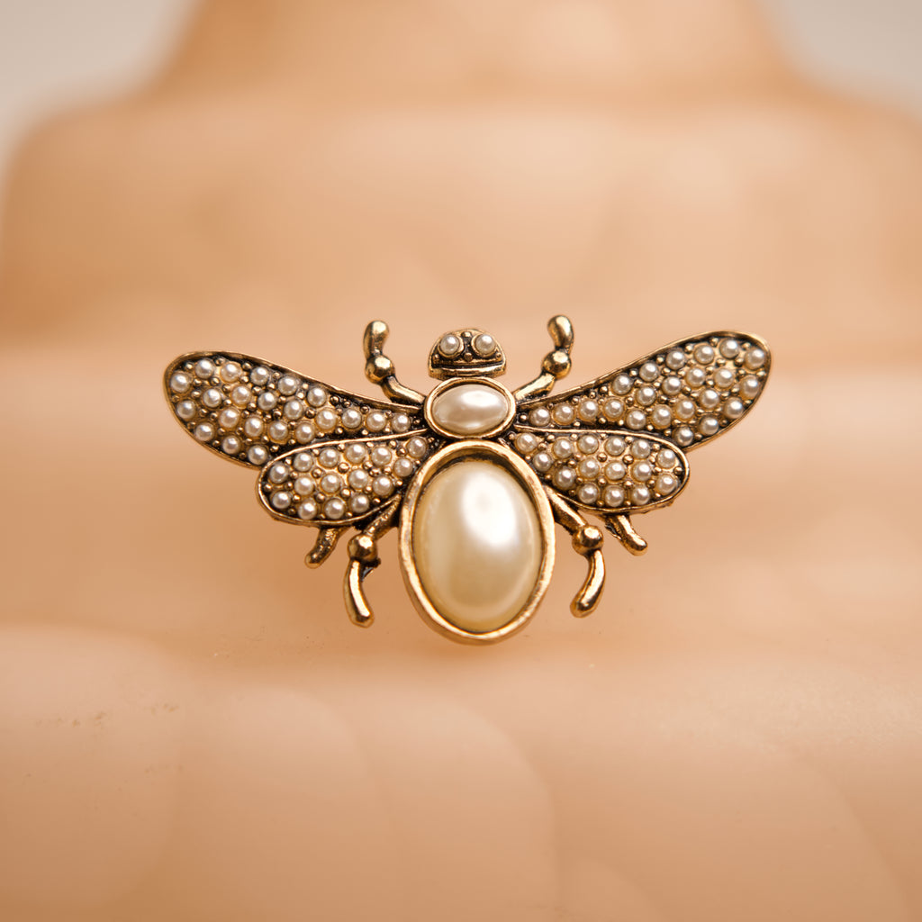 Gold bee-shaped brooch with pearl accents on a mannequin