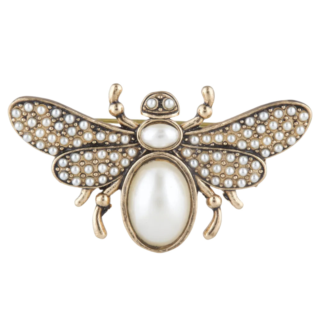 Decorative bee-shaped object with pearl-like stones on a white background