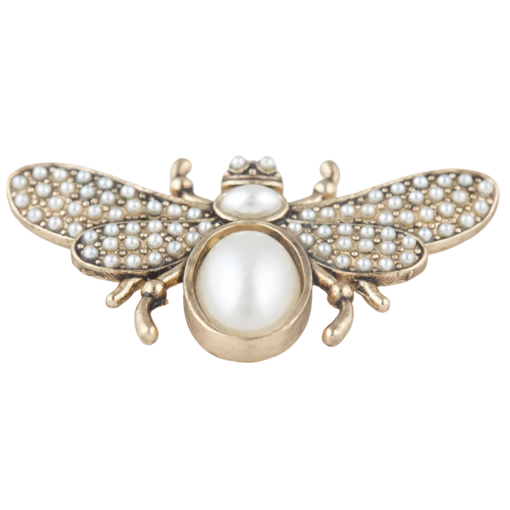 Gold bee-shaped brooch with pearl accents on a white background