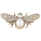 Gold bee-shaped brooch with pearl accents on a white background