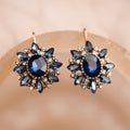 Pair of blue gemstone earrings on a beige background