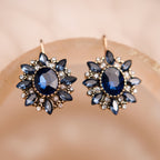 Pair of blue gemstone earrings on a beige background