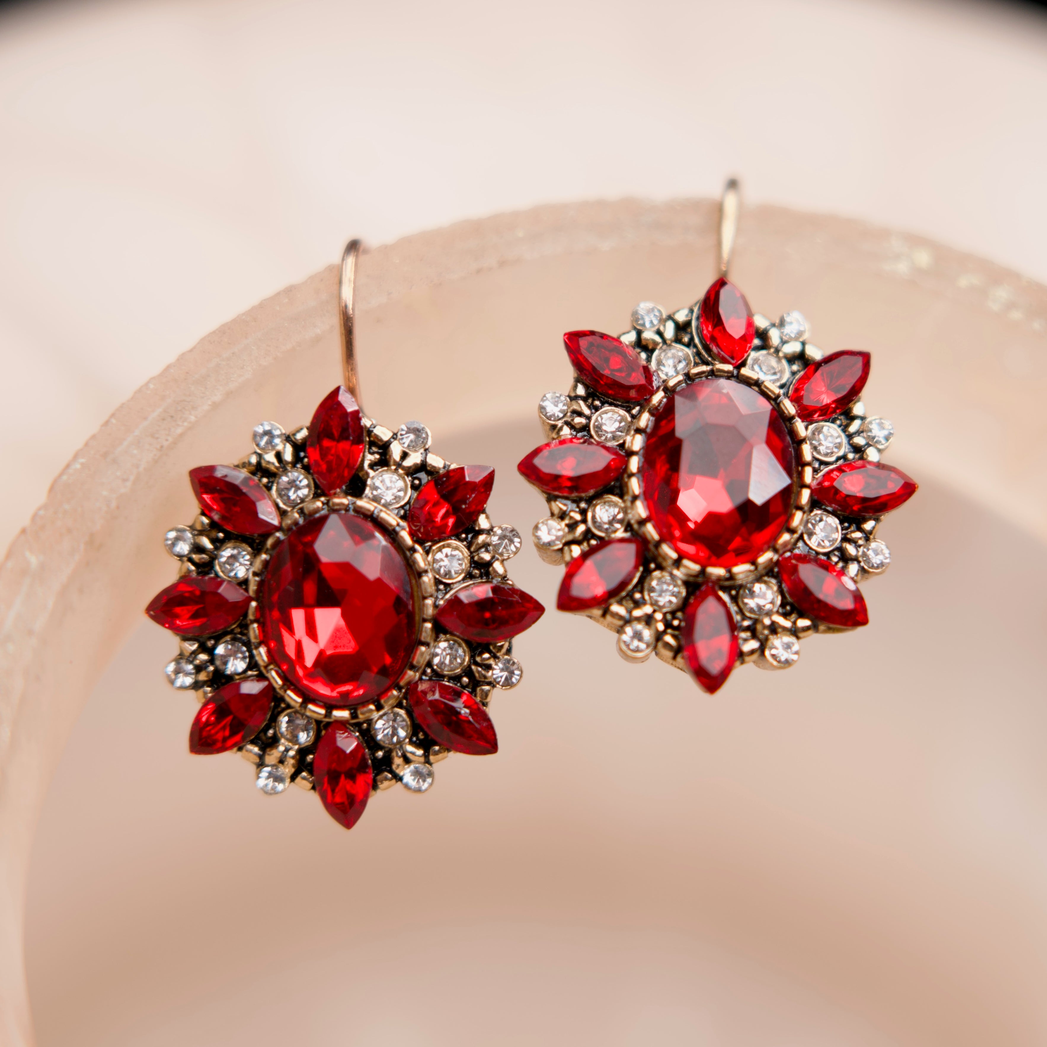 Pair of red gemstone earrings on a beige background