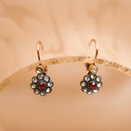Gold earrings with red gemstones on a beige background
