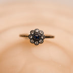 Ring with a central blue gemstone and smaller diamonds on a beige background