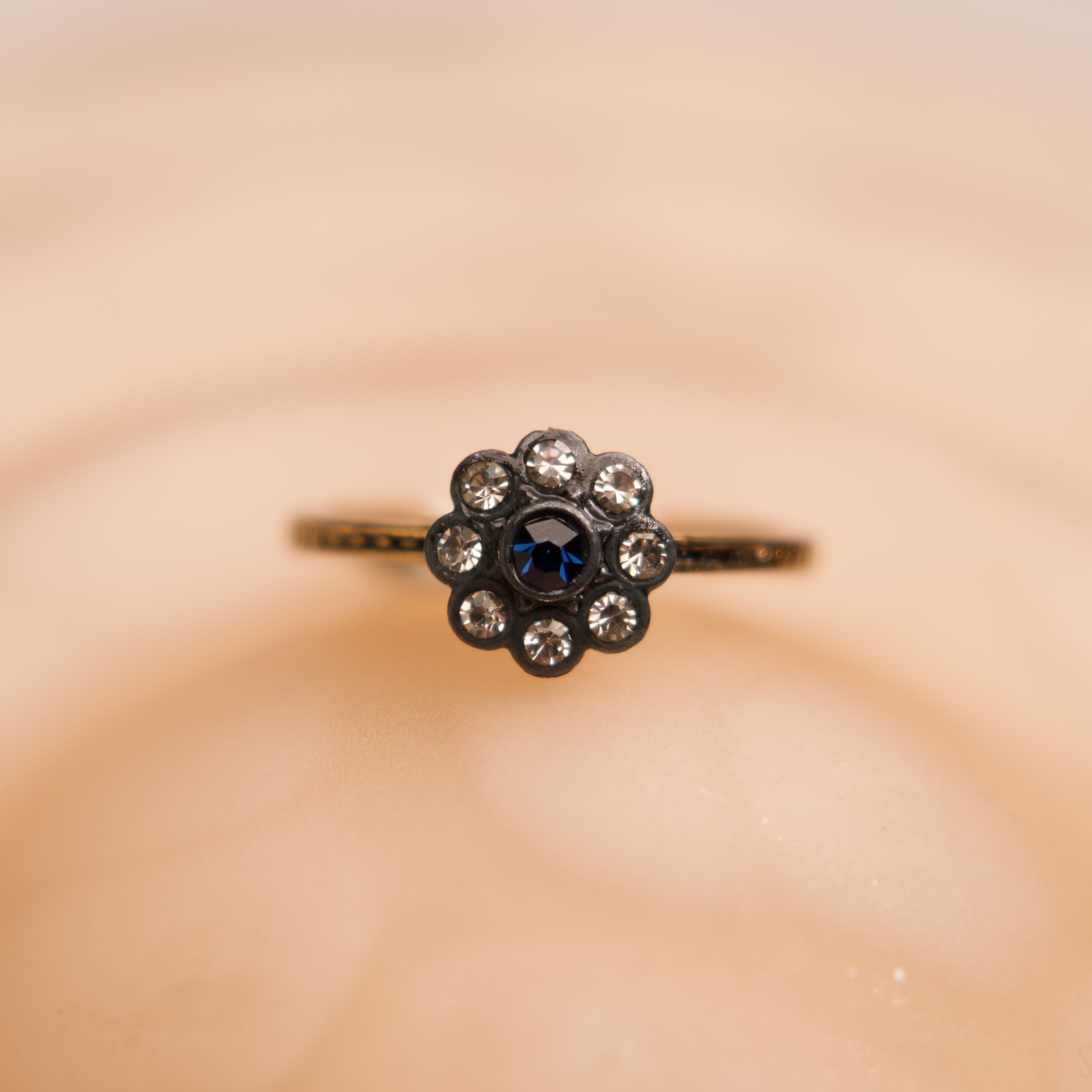 Ring with a central blue gemstone and smaller diamonds on a beige background