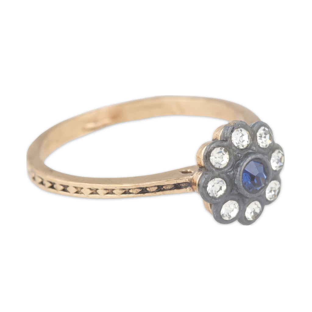 Gold ring with a blue gemstone and clear stones on a white background