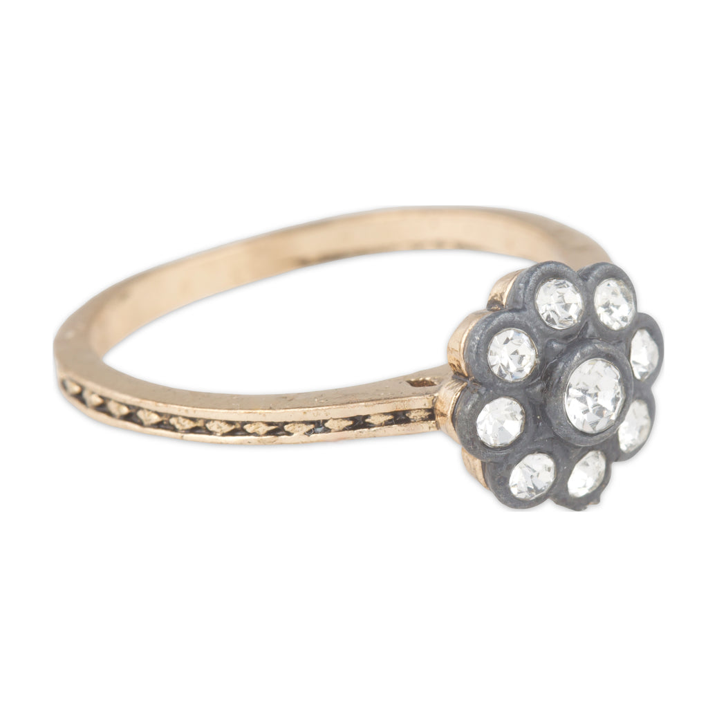 Gold ring with a decorative flower-shaped gemstone on a white background
