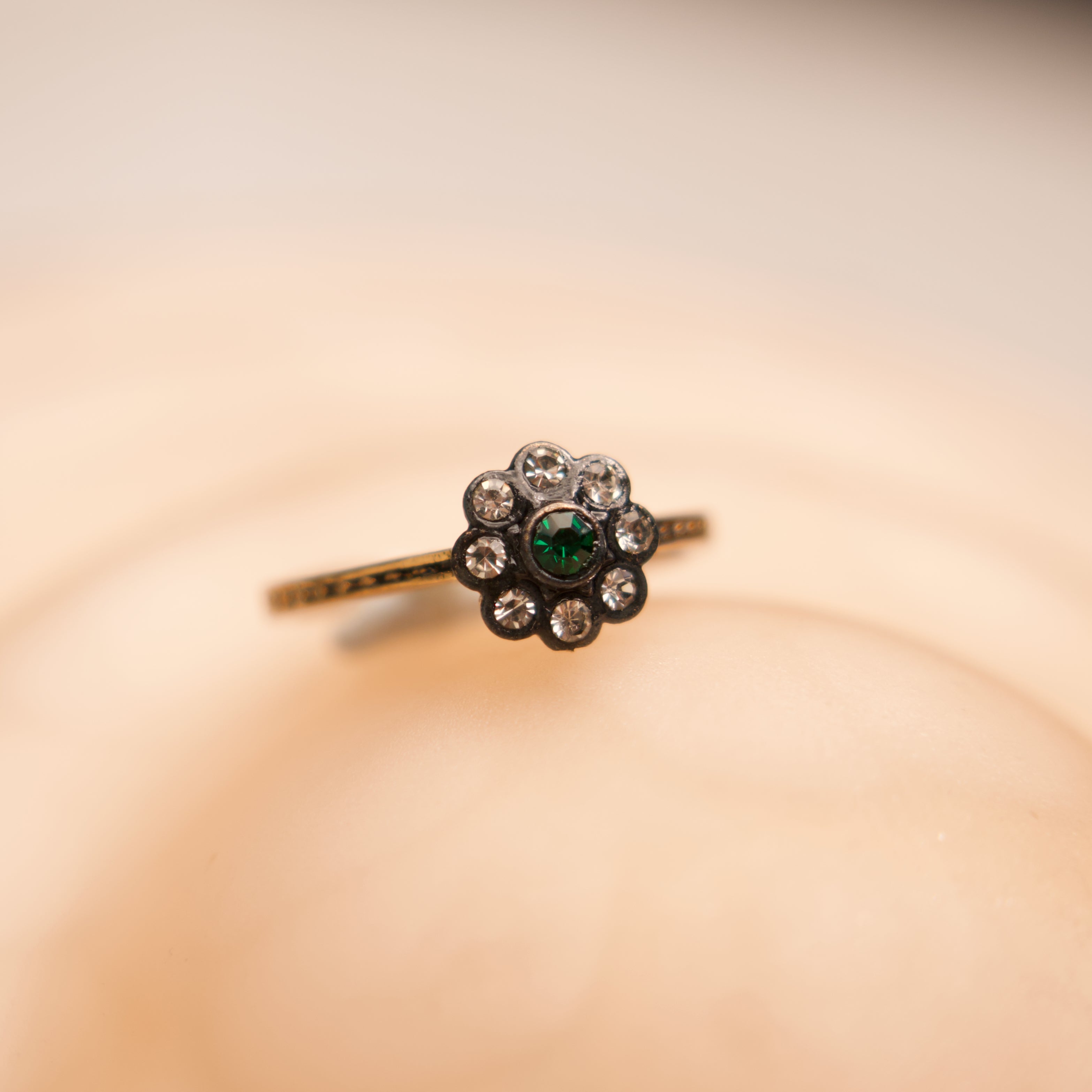 Delicate ring with a green gemstone on a soft beige background
