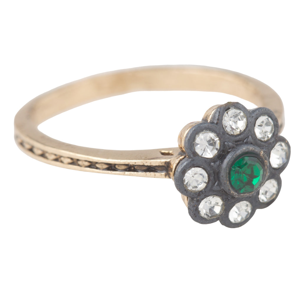 Gold ring with a floral design featuring green gemstone and clear stones on a white background