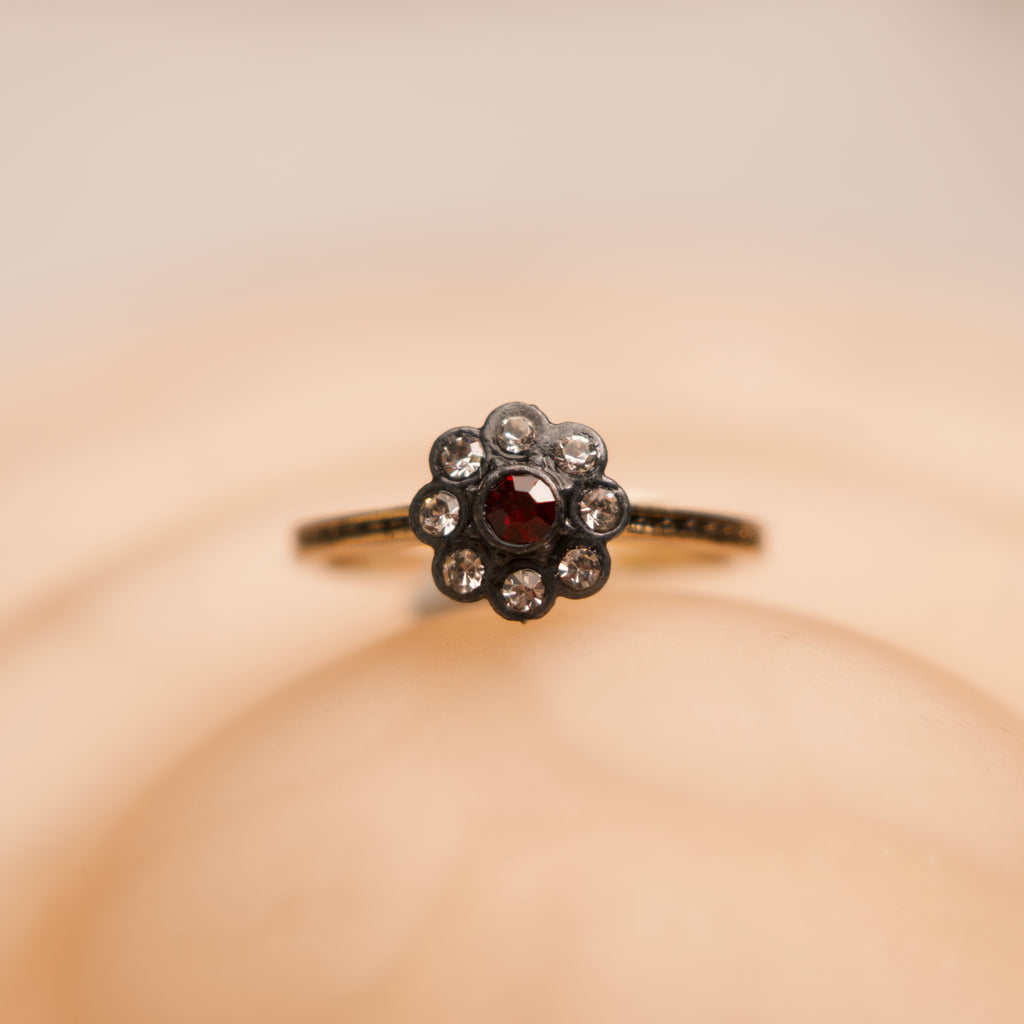 Floral ring with a central gemstone on a beige background