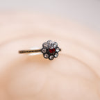 Decorative hairpin with a red gemstone and clear stones on a soft pink background