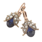 Pair of earrings with blue teardrop stones and rose gold accents on a white background