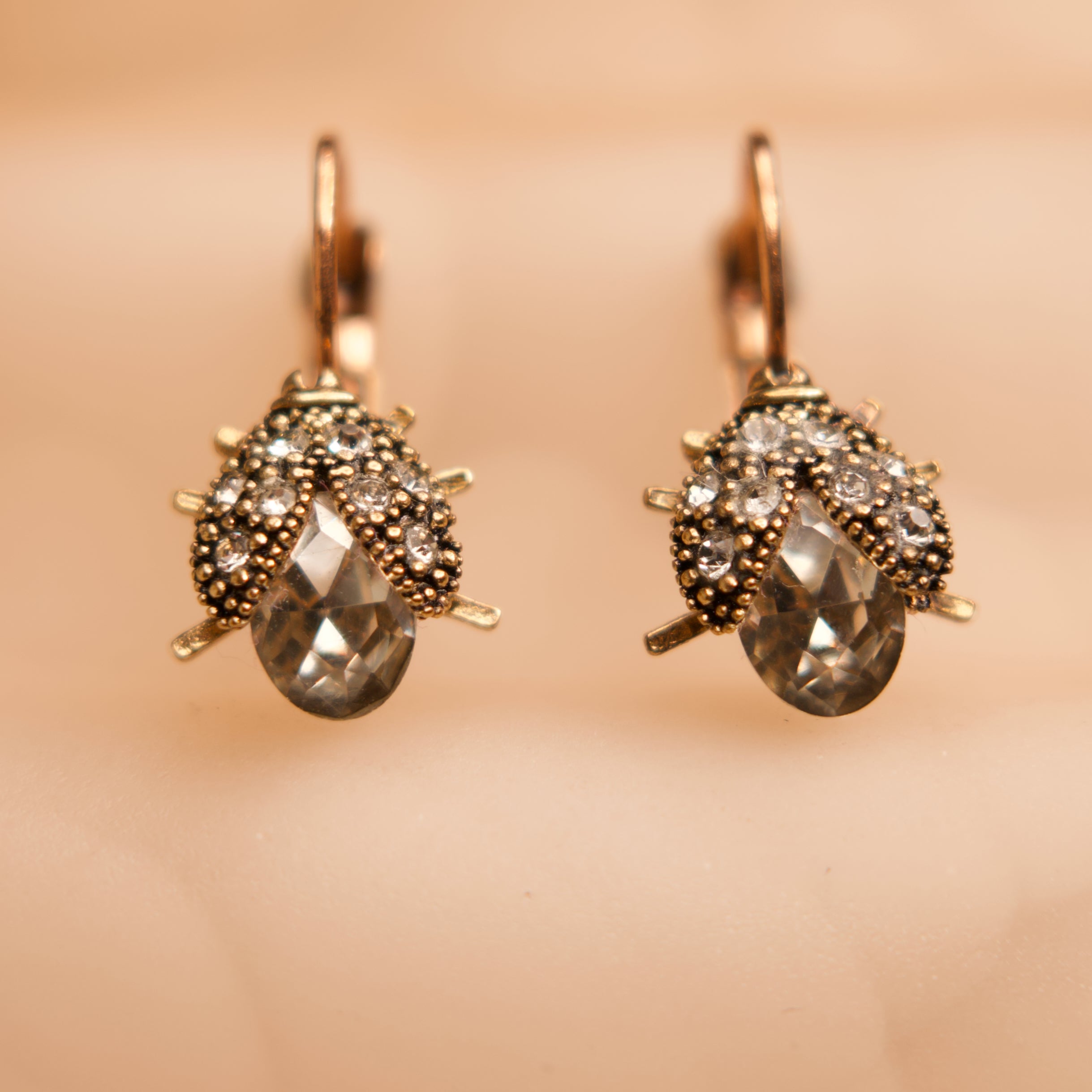 Pair of gold earrings with gemstones on a beige background