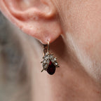 Close-up of an ear wearing a dangling earring with a blurred background