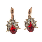 Pair of earrings with red teardrop-shaped gemstones and gold accents on a white background