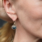 Close-up of a woman wearing a gold earring with gemstones.