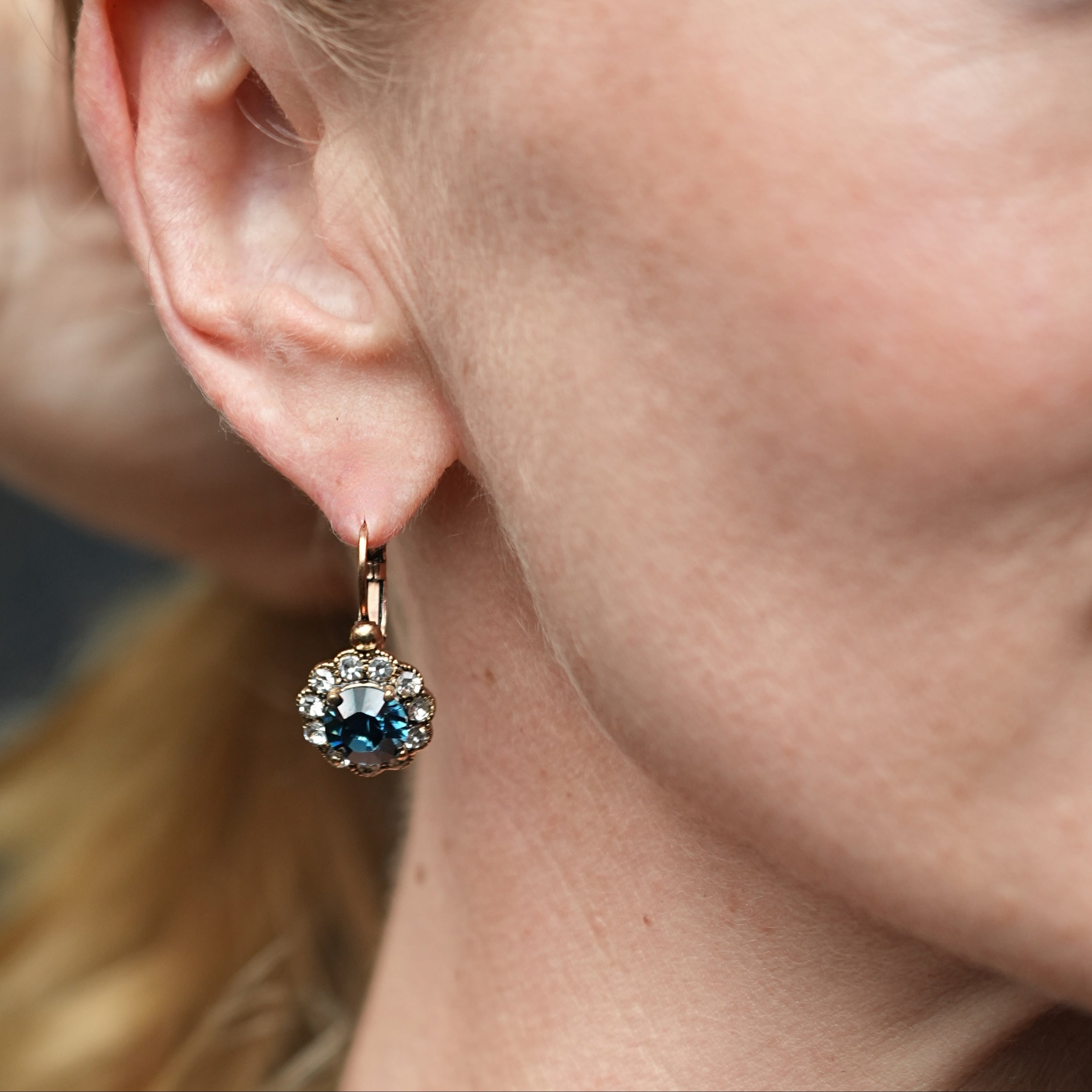 Close-up of a woman wearing a gold earring with gemstones.