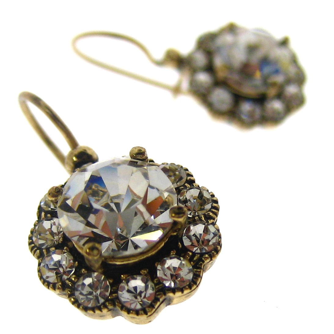 Pair of ornate earrings with clear gemstones on a white background