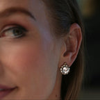 Close-up of a woman's ear wearing a decorative earring with a blurred background