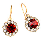 Gold earrings with red gemstones on a white background