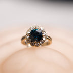 Gold ring with a blue gemstone on a soft beige background