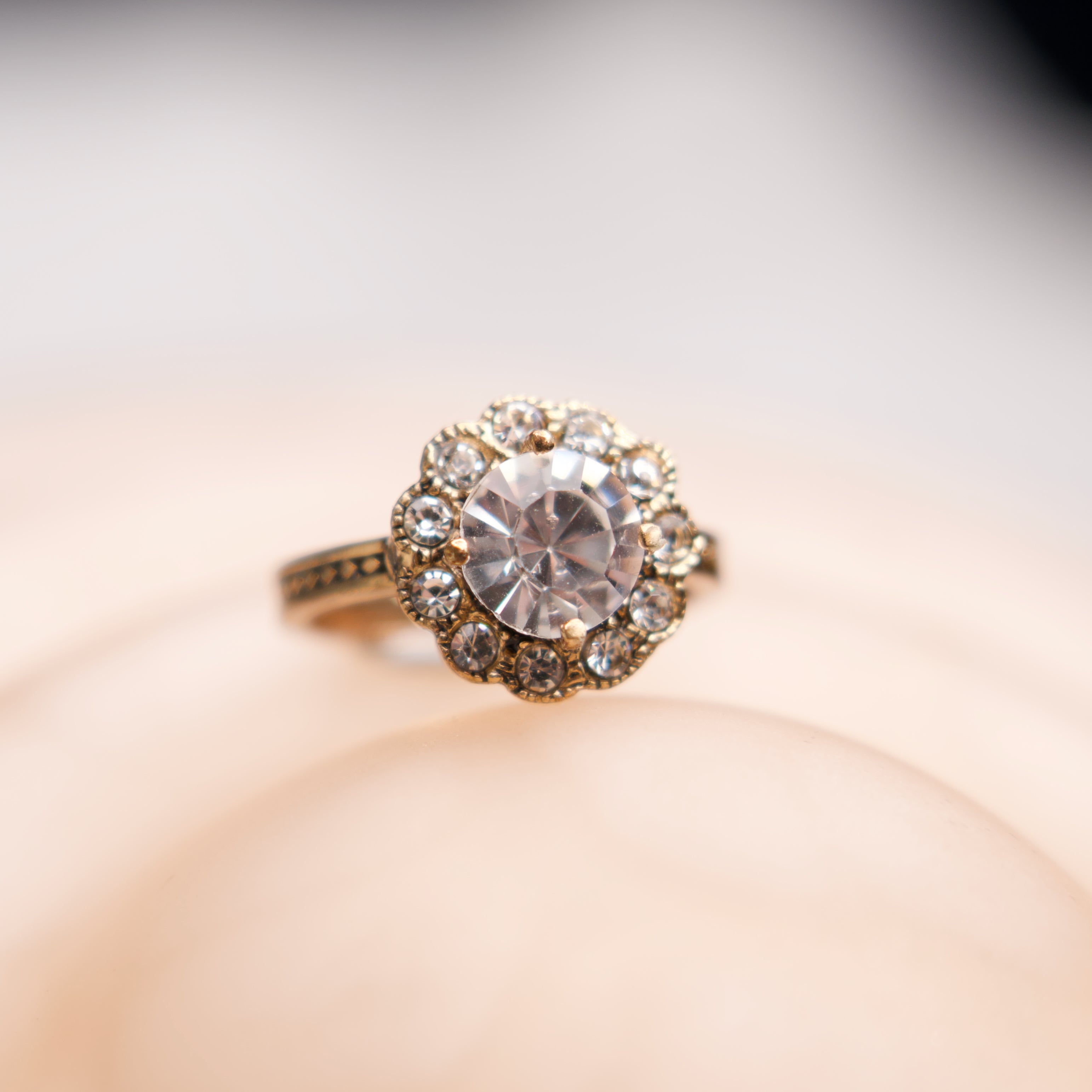 Gold ring with a large diamond and smaller stones on a soft focus background
