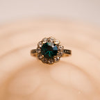Gold ring with a green gemstone on a beige background