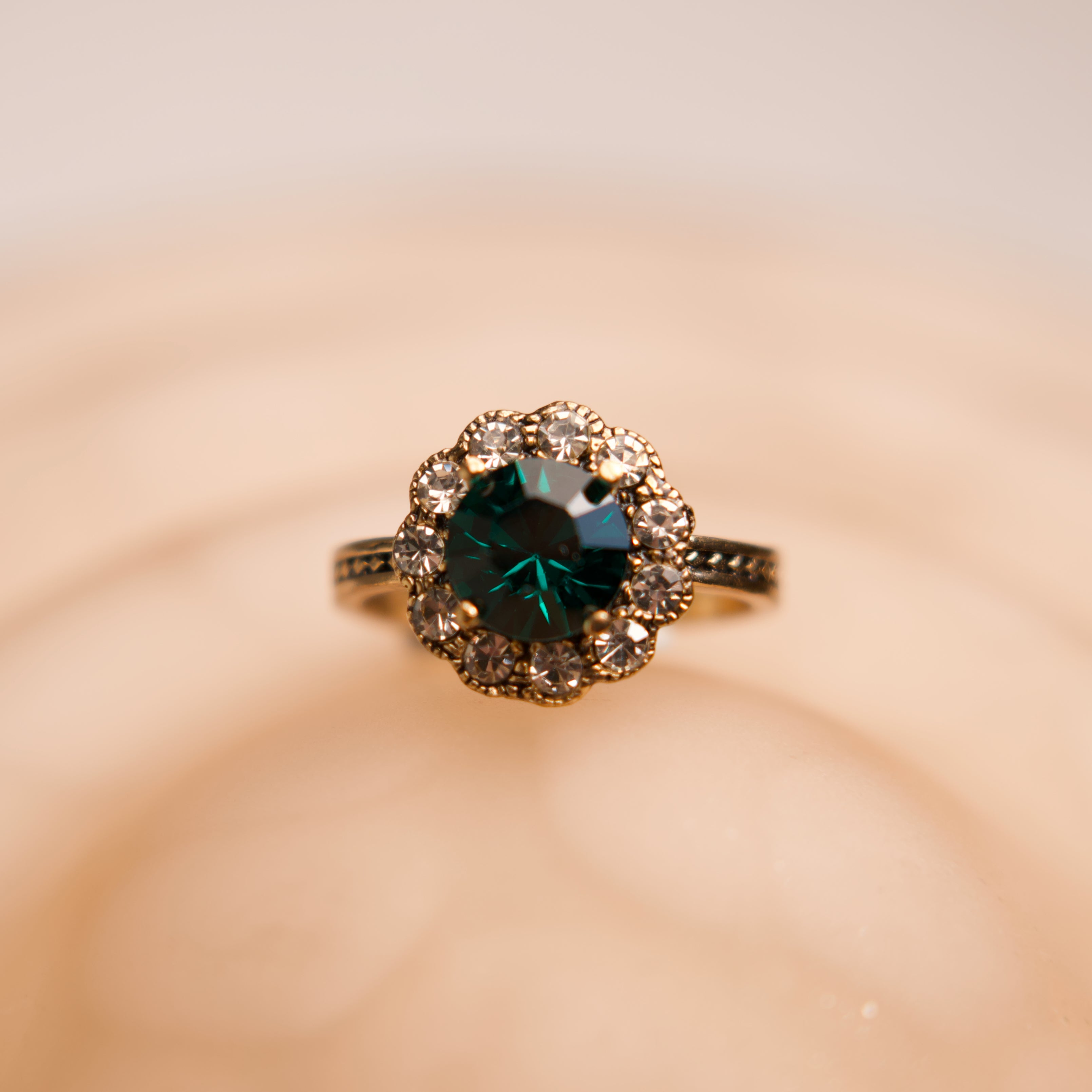 Gold ring with a green gemstone on a beige background