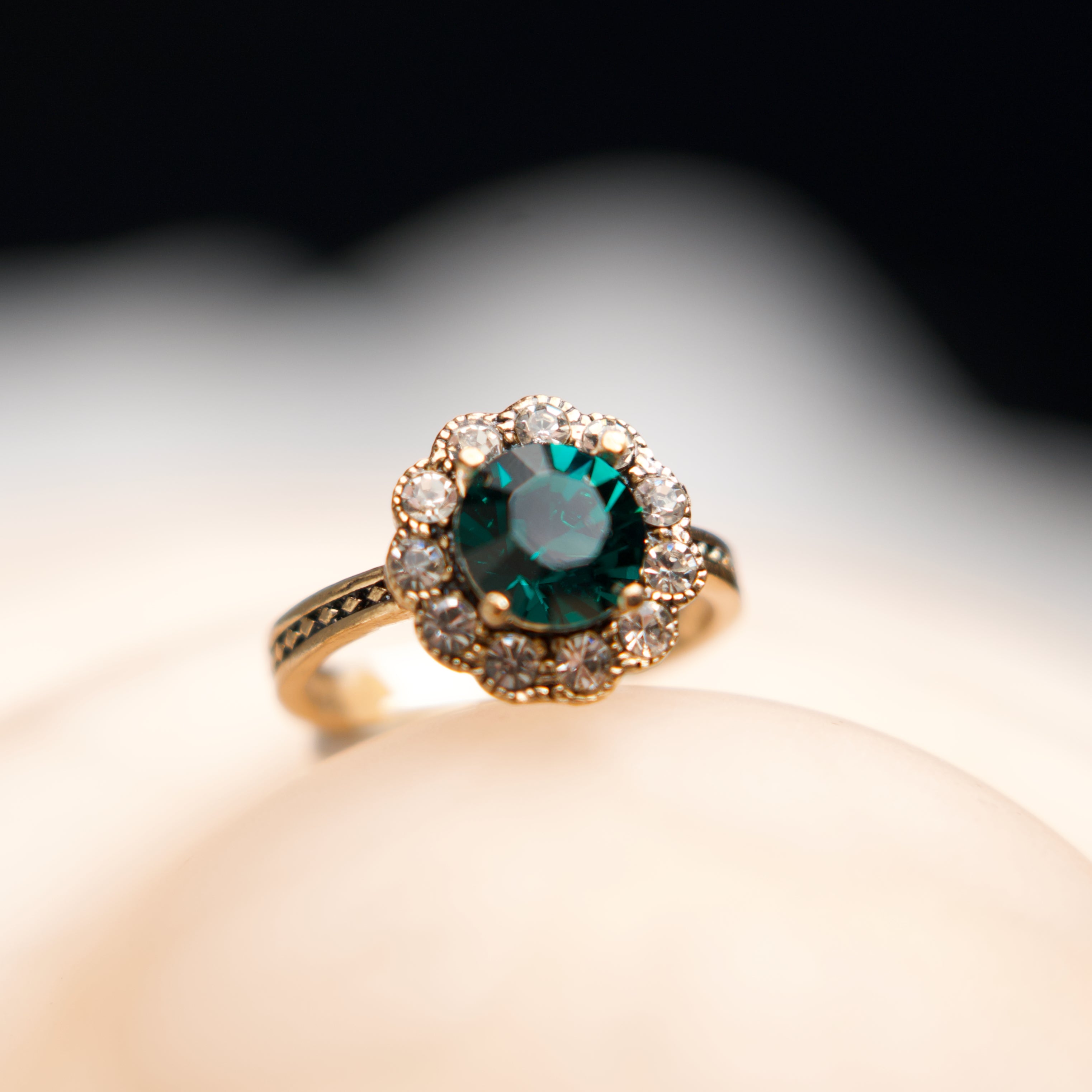 Gold ring with a green gemstone on a blurred background