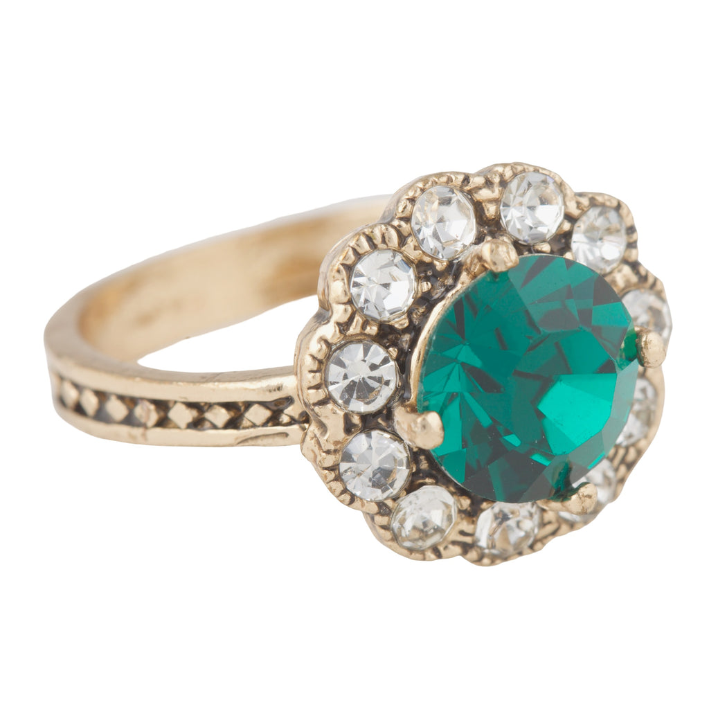 Gold ring with a green gemstone and clear stones on a white background