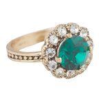 Gold ring with a green gemstone and clear stones on a white background