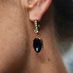 Close-up of an earring with a black gemstone on a person's ear.